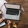 A top-down view of a laptop, coffee cup, chocolate, and a USB hub on a wooden desk. Produktbild-Vorschau