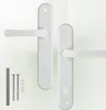 Two white door handles with backplates and some screws and caps are displayed against a white background. Náhled obrázku produktu