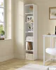 A tall, narrow white bookshelf filled with decorative items and books, placed next to a window in a room with light beige walls and wooden flooring. Produktbild-Vorschau