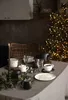 A table setting for a holiday gathering with a Christmas tree in the background. Náhled obrázku produktu