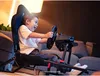 A young boy is excitedly playing a racing video game using a racing wheel and cockpit setup in a living room. Produktbild-Vorschau