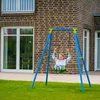 A young girl is happily swinging on a blue and green swing set in front of a brick house. Produktbild-Vorschau