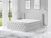 A light gray upholstered boxspring bed with a tufted headboard and two storage drawers, shown in a bedroom setting with a window and artwork on the wall. Produktbild-Vorschau