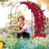 A woman gardening in front of a rose-covered arch. Podgląd zdjęcia produktu