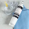 A Whirlpool water filter is placed next to a glass of water with a lemon slice and ice cubes, on a textured surface and a blue waffle-weave cloth. Anteprima dell’immagine prodotto