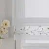 A close-up view of a white sheer Roman blind with embroidered daisies and green vines. Produktbild-Vorschau