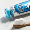 A close-up shot of a tube of Marvis toothpaste and a toothbrush with toothpaste on it. Náhled obrázku produktu