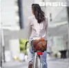 A woman rides a bicycle with a basket on the back, carrying groceries. Náhľad obrázku produktu