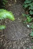 Two decorative stepping stones are placed on a path covered with wood chips, surrounded by greenery. Produktbild-Vorschau
