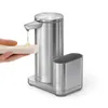 A hand is holding a sponge under a soap dispenser that is dispensing liquid soap. Produktbild-Vorschau