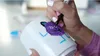 A person is decorating a white mug with a purple monster drawing using markers. Produktbild-Vorschau