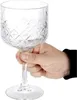 A hand holding a clear, patterned glass. Náhled obrázku produktu