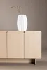 A white vase with a branch sits on top of a light wood cabinet. Produktbild-Vorschau