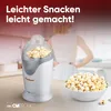 A woman stands in a kitchen with a popcorn maker and a bowl of popcorn. Náhled obrázku produktu