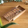 A wooden board game with colored pegs and wooden dowels is placed on a wooden table. Náhľad obrázku produktu
