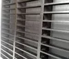 A close-up, diagonal view of a black, slatted shelf or rack, showing its grid-like structure. Produktbild-Vorschau
