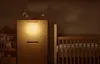 A night light is attached to a wooden cabinet in a nursery, next to a crib. Podgląd zdjęcia produktu