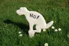 A white dog statue in a squatting position with the word "NO!" on its back, placed in a grassy area with small white flowers. Produktbild-Vorschau