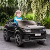 A young boy is driving a black toy electric car in an outdoor setting with lush greenery and white flowers. Náhľad obrázku produktu