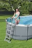 A woman is getting into an oval above-ground swimming pool with a ladder. Anteprima dell’immagine prodotto