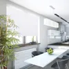 A modern kitchen and dining area with a white table and chairs, a white roller blind on the window, and a large plant. Produktbild-Vorschau
