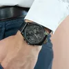 A man wearing a white dress shirt and blue pants, showing off his Tommy Hilfiger watch. Produktbild-Vorschau