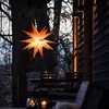 An illuminated star lantern hangs from a tree on a wooden deck at dusk, with outdoor furniture visible. Produktbild-Vorschau