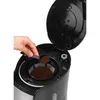 A hand is adding coffee grounds to a coffee maker. Produktbild-Vorschau