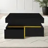 A modern black coffee table with gold accents and drawers, placed on a rug in a well-lit room.