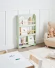 A child's bookshelf filled with books and decorative items, placed in a room with a small chair and table. Náhled obrázku produktu