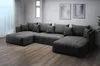 A large, dark gray sectional sofa is shown in a well-lit room with a wooden floor and two framed pictures on the wall. Produktbild-Vorschau