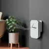 A wireless doorbell receiver is mounted on a gray wall next to a potted plant, with musical notes emanating from the doorbell. Náhľad obrázku produktu