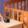 A stained glass cat lamp sits on a nightstand next to a crib where a baby is sleeping. Produktbild-Vorschau