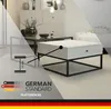 A modern living room scene featuring a white coffee table with a black metal frame and a drawer, with a diagram indicating its thickness. Voir les images du produit