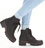 A person wearing light blue jeans and black boots. Produktbild-Vorschau
