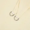 A close-up view of a cream-colored fabric sail with two metal D-rings attached to reinforced corners. Produktbild-Vorschau