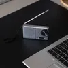 A small portable radio and a laptop are placed on a black surface. Voir les images du produit