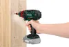 A hand is holding a cordless drill and screwing it into a wooden post. Produktbild-Vorschau