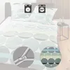 A bed with bedding featuring a circular pattern. Icons indicating washing instructions are present. Produktbild-Vorschau