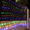 A fence decorated with colorful net lights at night. Produktbild-Vorschau