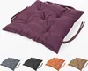 A single purple seat cushion is shown from a diagonal angle, with four other colored seat cushions (gray, black, orange, brown) displayed below it. Produktbild-Vorschau