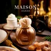 A perfume bottle is displayed on a table with sweets and a honey dipper, with a camera in the background. Voir les images du produit