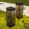 Two black solar garden lights with intricate cutouts are placed on a green lawn next to a path of white gravel. Produktbild-Vorschau