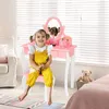 A young girl sits on a stool in front of a pink vanity table in a bedroom. Voir les images du produit