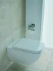A wall-mounted toilet with a toilet paper holder attached to a white column next to it. Produktbild-Vorschau