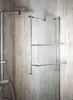 A chrome towel rack mounted on a glass shower door with marble-patterned walls in the background. Produktbild-Vorschau