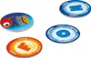 Four circular game tokens are arranged on a white background. One token is stacked on top of others, showing a cartoon character and text. The other three tokens are laid out individually, each displaying a large letter and text around the edge. Produktbild-Vorschau