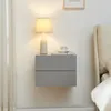 A bedside table with a lamp and a cup on it, next to a bed. Produktbild-Vorschau