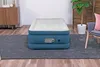 An inflatable air mattress is placed on a dark gray rug in a room with wooden flooring and furniture. Produktbild-Vorschau