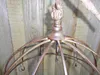 Close-up of a metallic gold hanging rack with hooks, against a weathered wooden fence. Produktbild-Vorschau